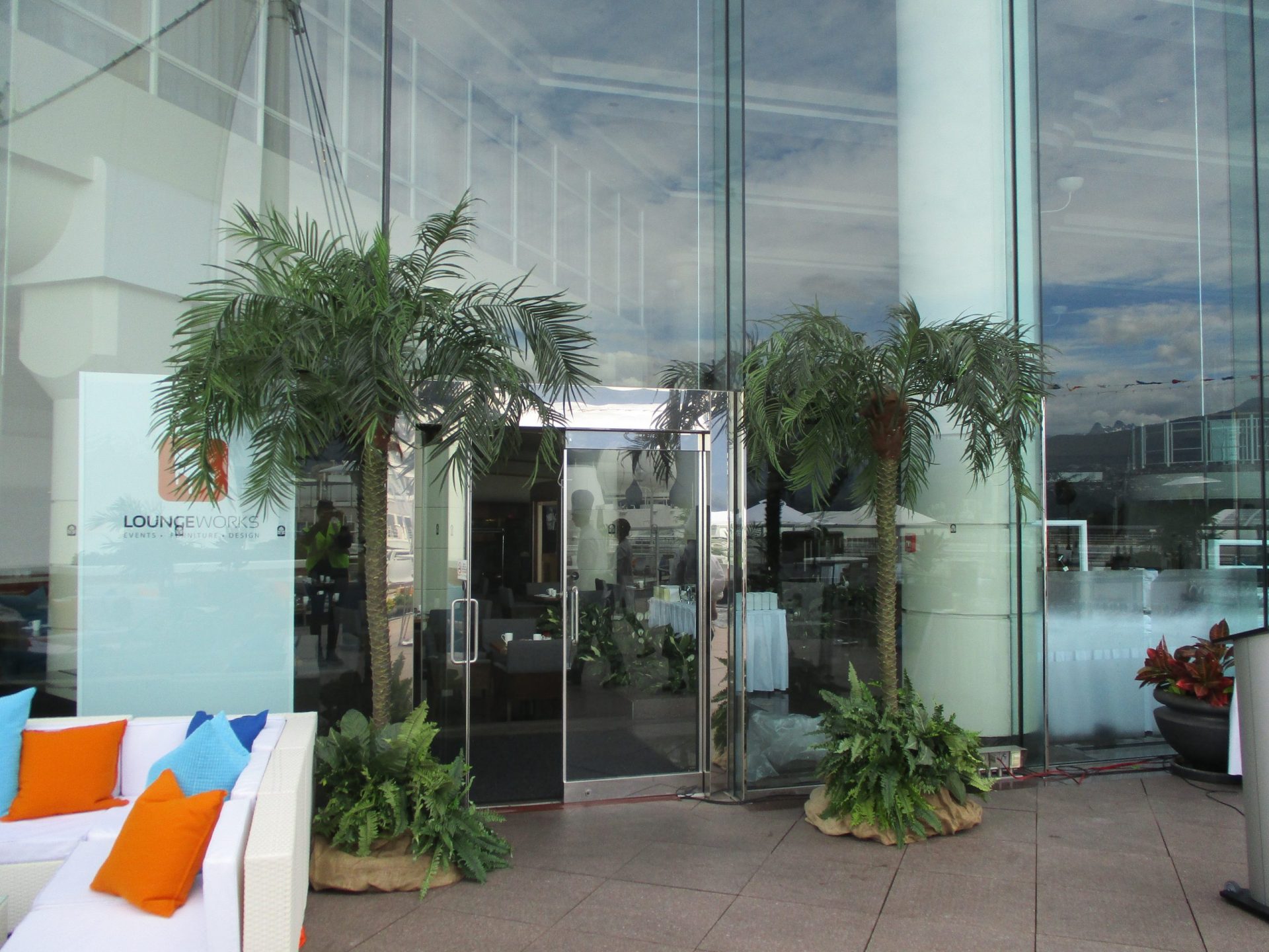 Two tall phoenix palm trees with tropical base gardens flanking door entrance for event