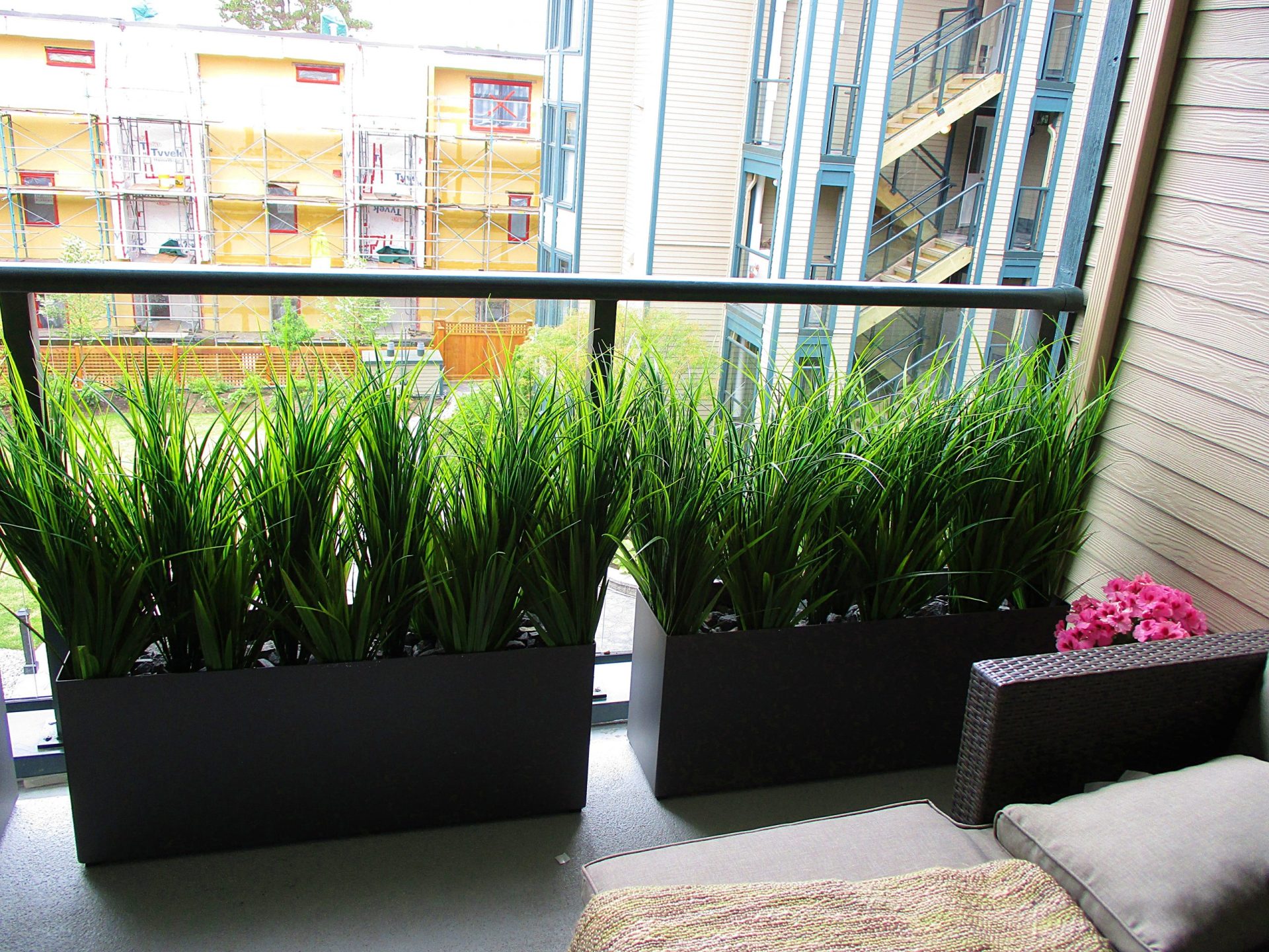 Artificial tall grass in aluminum planters for residential balcony decor and privacy