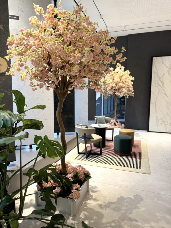 Artificial 8-foot cherry blossom tree with soft pink blooms in a white interlocking planter, styled for elegant event or showroom décor.