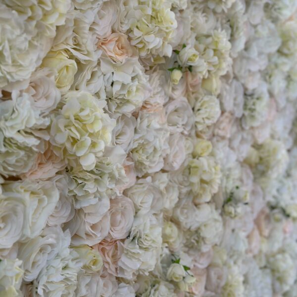 Close-up of a white and cream faux floral wall with roses and hydrangeas in soft neutral tones.