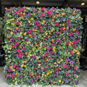 Large greenery wall backdrop filled with colourful wildflowers used as a vibrant event photo background