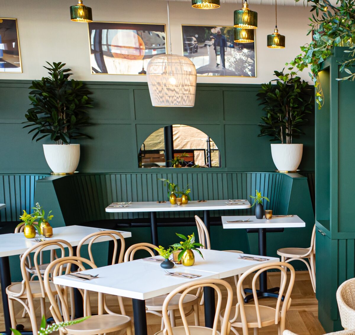 Restaurant dining room styled with artificial potted trees and floral centrepieces.