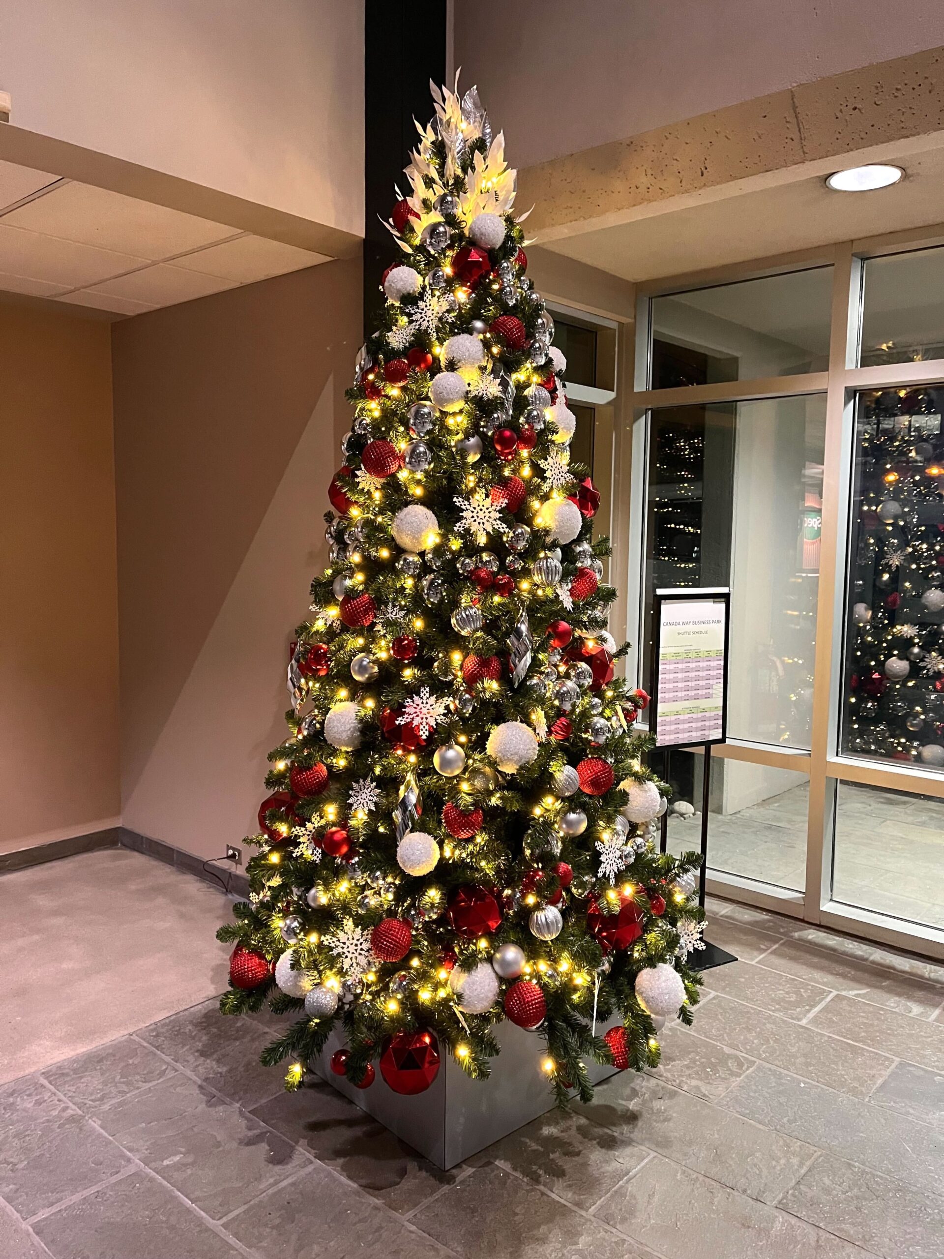 Modern red, white, and silver commercial Christmas tree display in an office lobby by Greenscape Design in Vancouver, perfect for hassle-free decorating