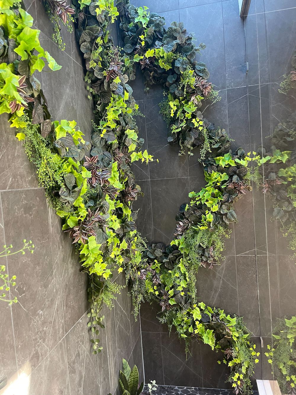 Artificial greenery and ivy climbing on a residential tile wall