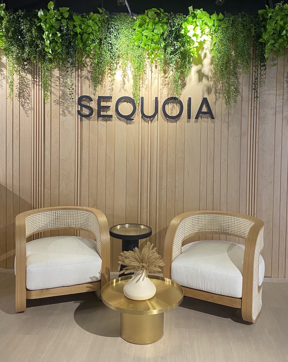 aux hanging greenery by Greenscape Design at Sequoia Presentation Centre in Vancouver, against a wood wall.