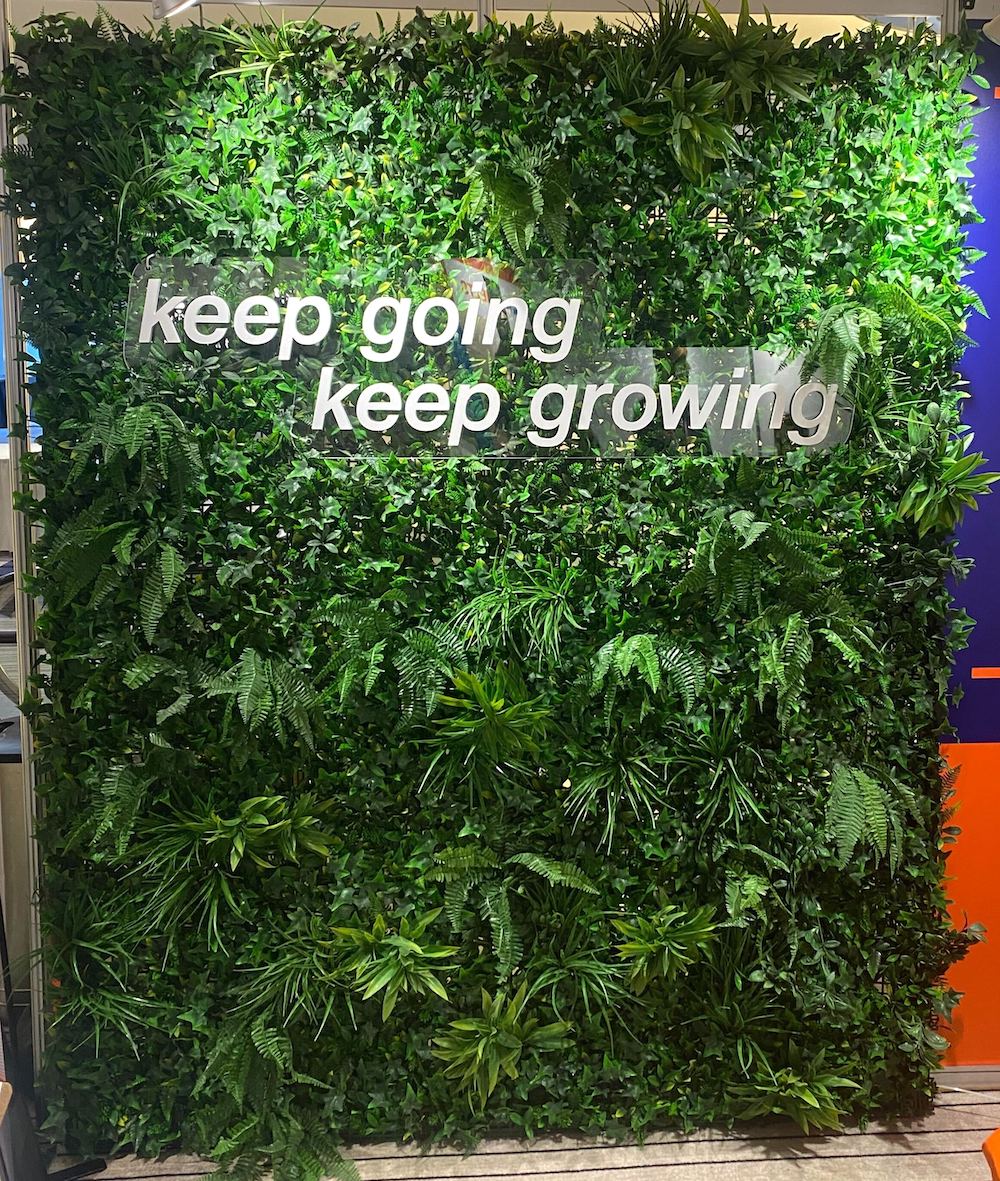 Artificial mixed greenery backdrop with custom branded logo and signage by Greenscape Design.