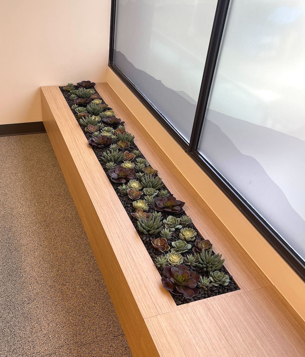 Artificial succulent planter by Greenscape Design embedded in a bench in an office setting.