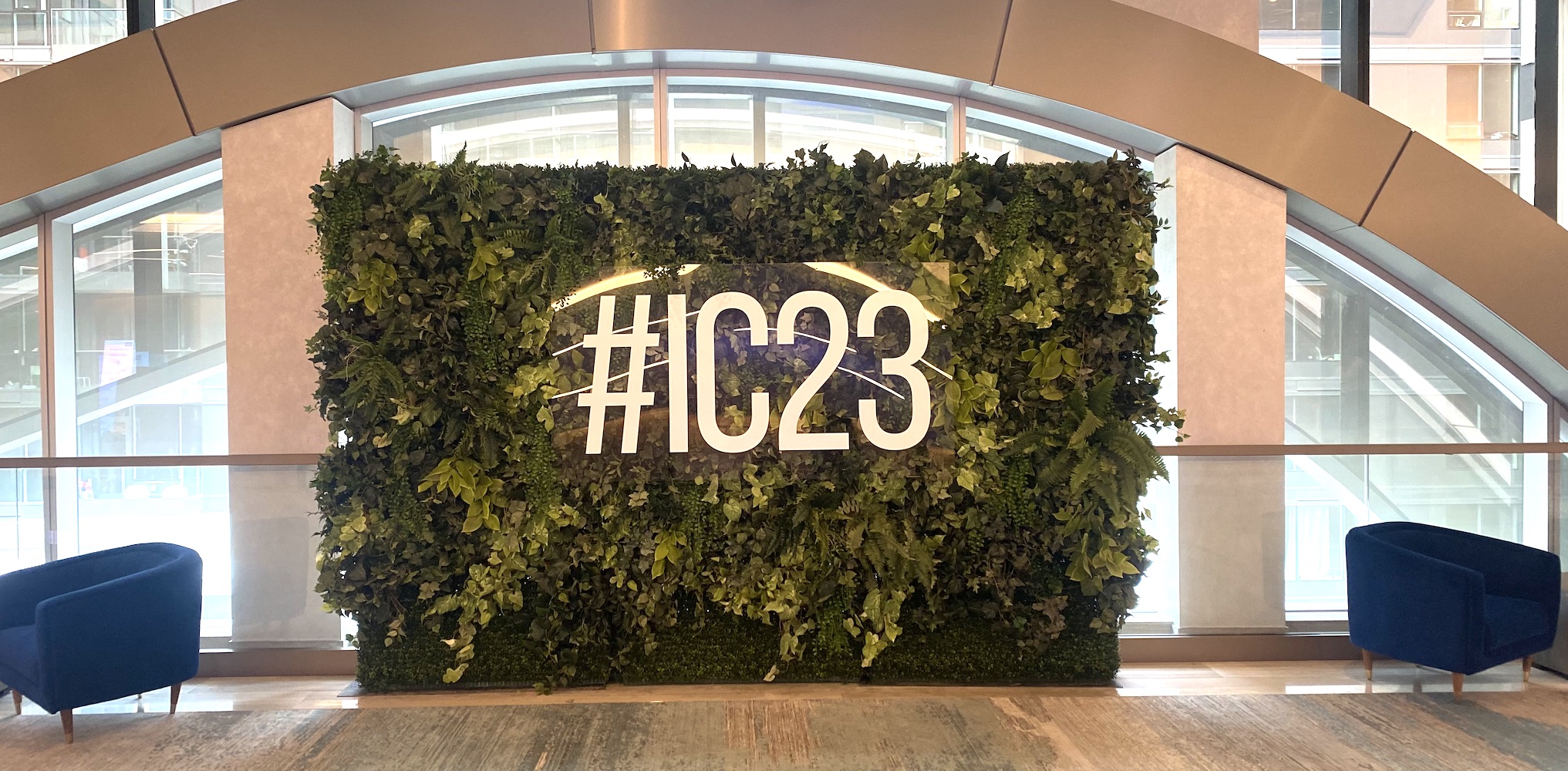 Boxwood hedge and mixed greenery backdrop rental with custom signage by Greenscape Design.