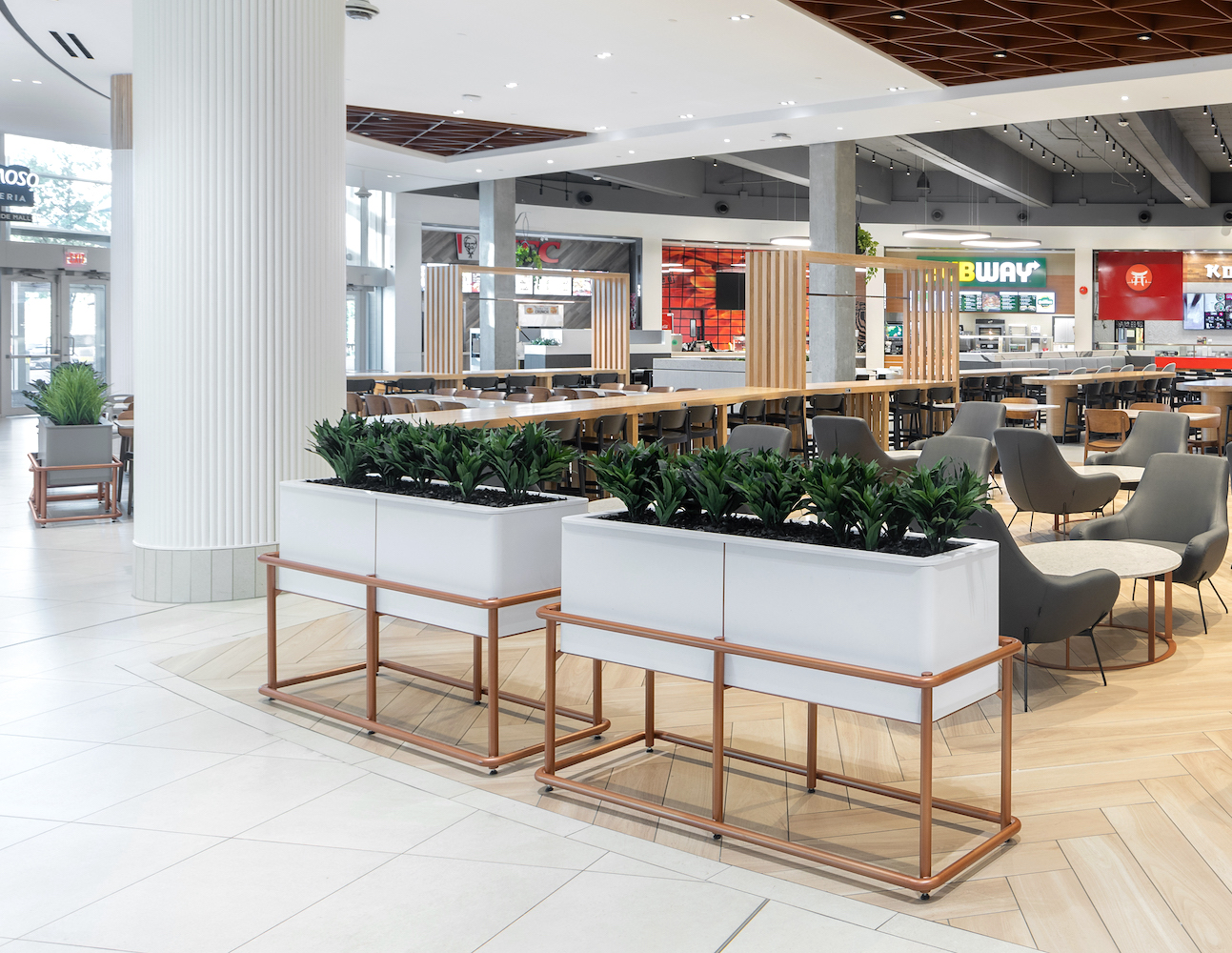 Modern white planters with artificial greenery by Greenscape Design line the seating area at Coquitlam Centre food court.