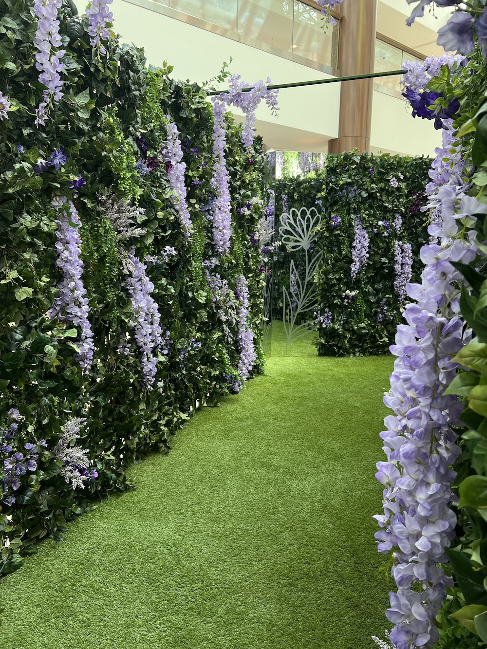 Green wall maze adorned with wisteria, creating an interactive display.