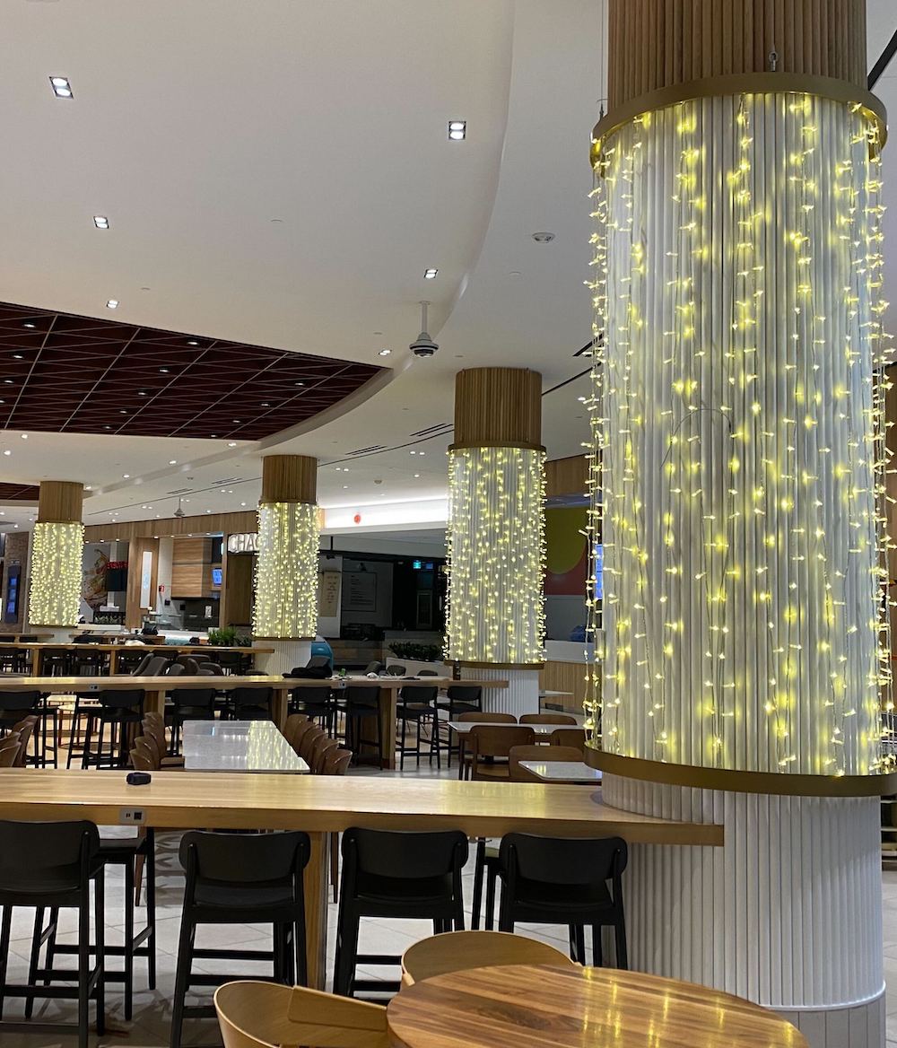 Greenscape Design enhances Coquitlam Centre with custom illuminated column decor, adding festive flair to the food court area.