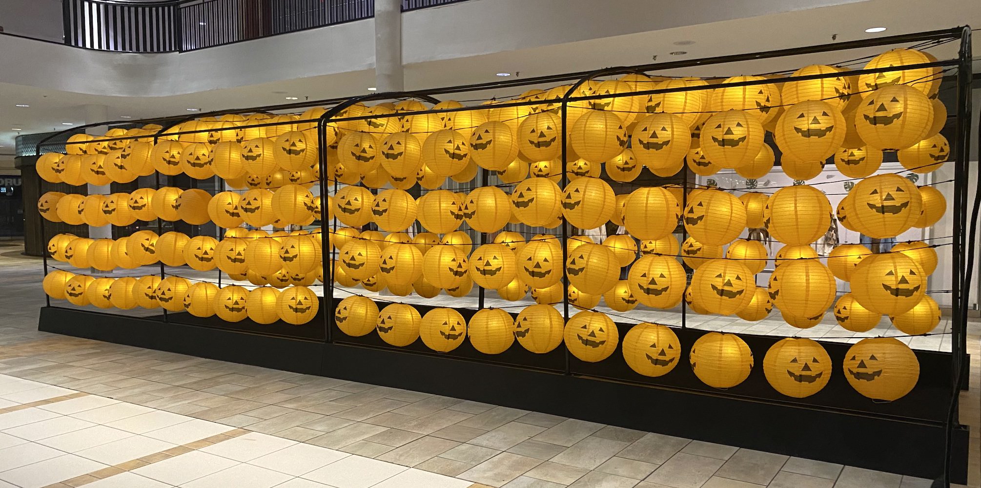 Hundreds of pumpkin lanterns creating an interactive Halloween tunnel display at The City of Lougheed by Greenscape Design.