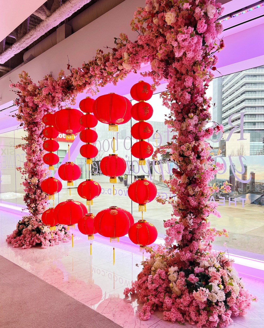 Custom Lunar New Year archway adorned with pink florals and red Chinese lanterns, designed by Greenscape Design.