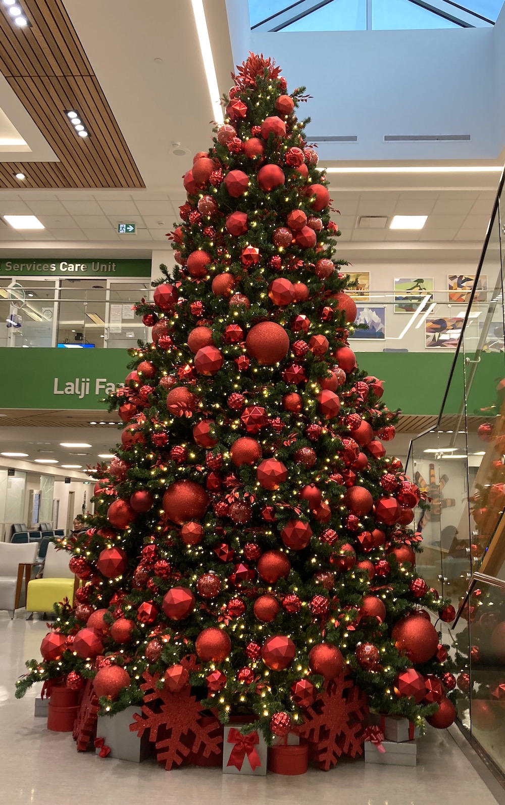 16' tall tower christmas tree decorated in modern monochromatic red ornaments in a hospital lobby.