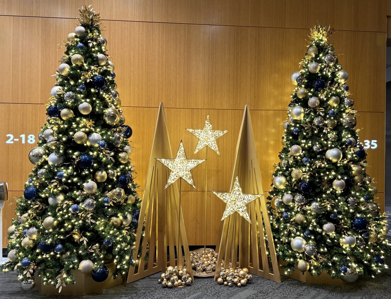 12ft tall Christmas trees and illuminated stars and wooden interlocking trees create a beautiful holiday backdrop against a wooden wall at Park Place office lobby in Vancouver.