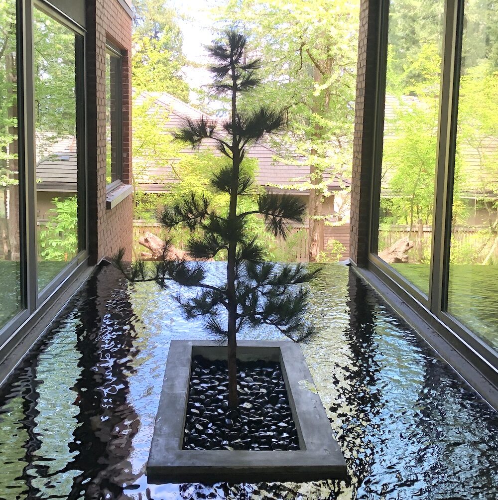 Artificial pine tree surrounded by a water pond