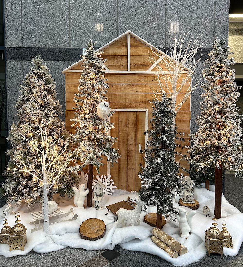Rustic cabin forest display featuring a flocked alpine tree, creating a picturesque photo backdrop.