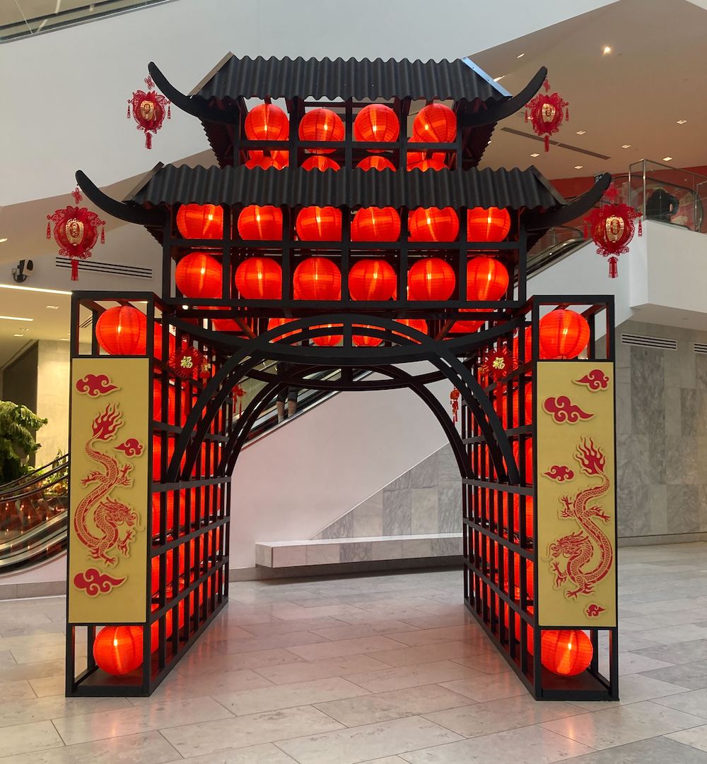 Vibrant Lunar New Year dragon display with a black pagoda, red lanterns and gold dragon etches by Greenscape Design at The Amazing Brentwood.