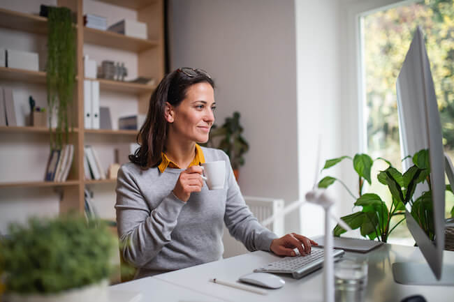 business woman sitting at her workspace decorated with faux indoor plants