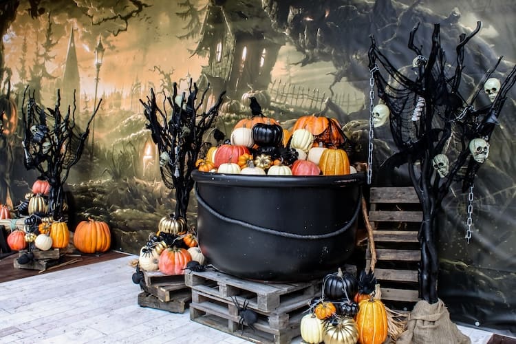 halloween decorations with faux plants and fake mini pumpkins in a cauldron