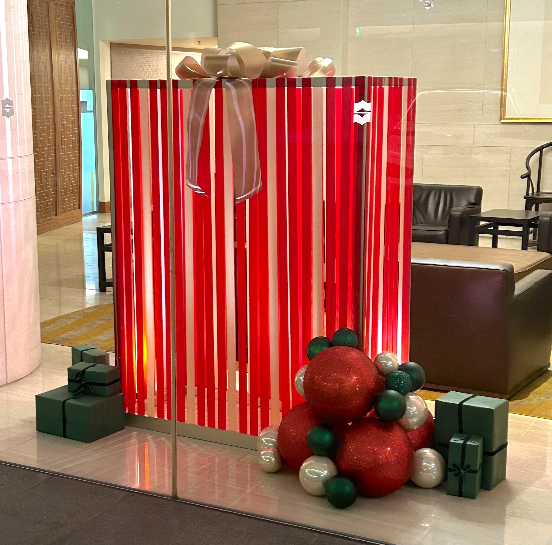 Custom-designed Christmas prop by Greenscape Design featuring a red-striped gift box with a gold bow, surrounded by festive ornaments and green gift boxes.