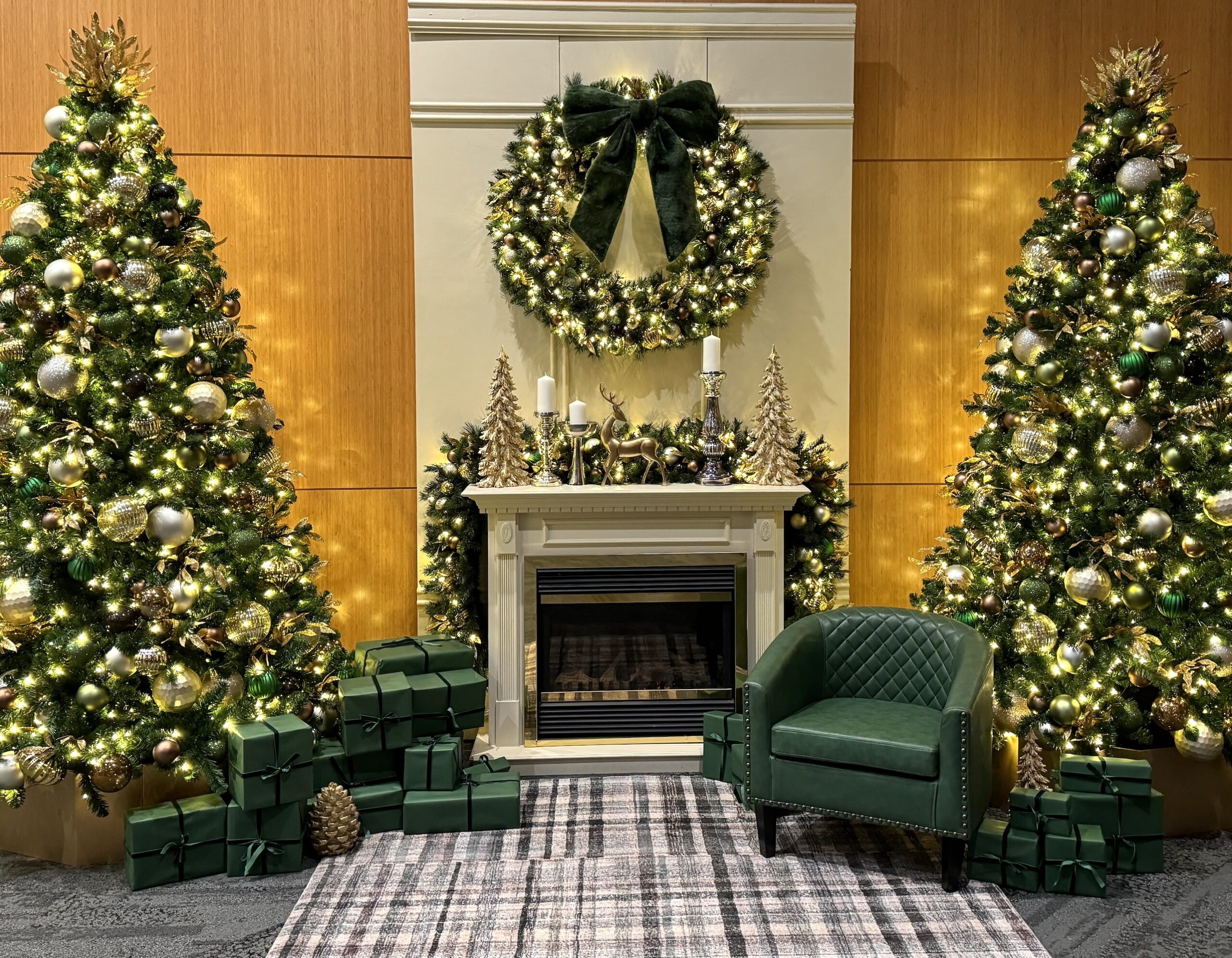 Luxurious Christmas display featuring a fireplace mantle, green and gold trees, and elegant holiday décor, designed for festive settings in Vancouver.