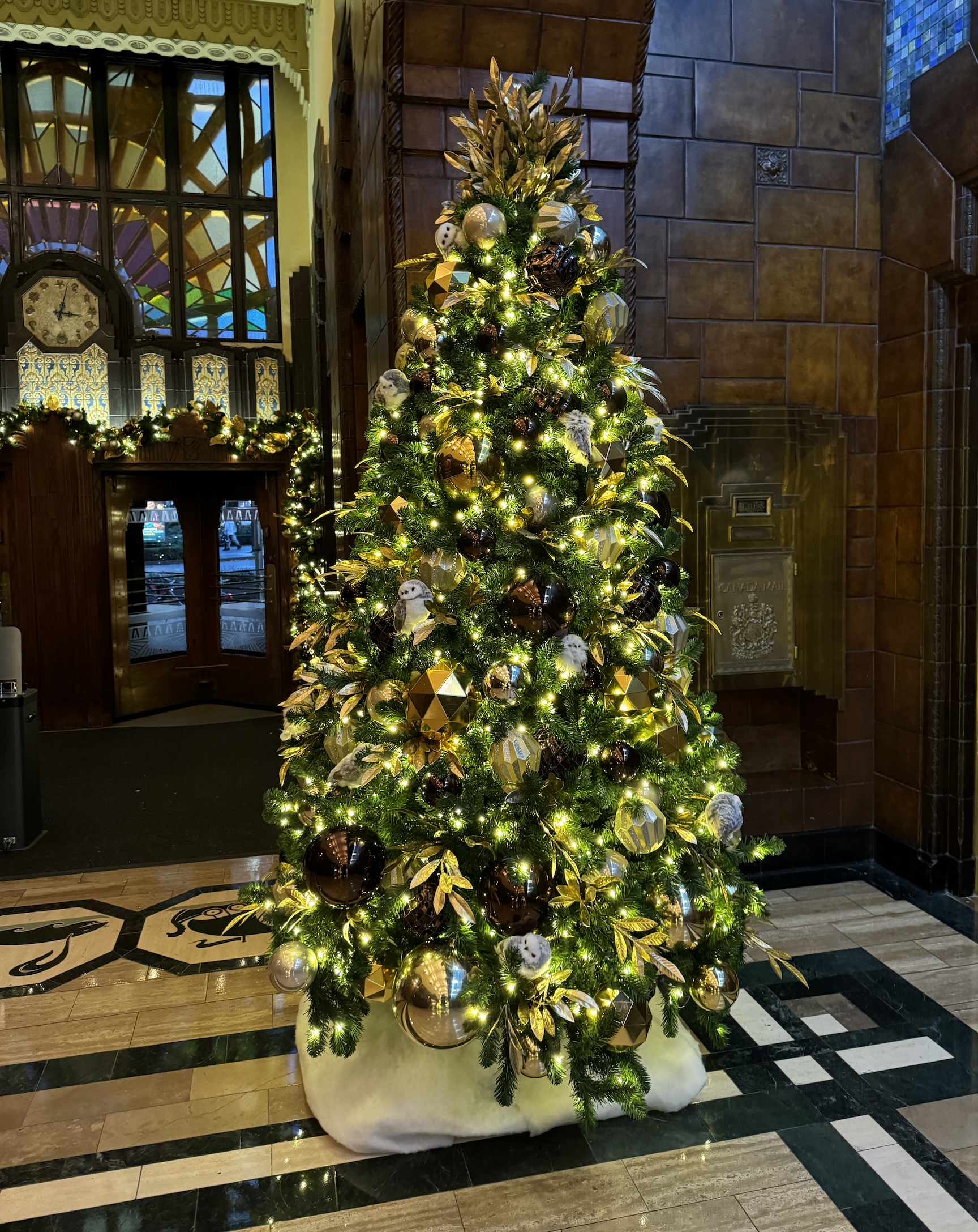 Mixed metallics Christmas tree with gold, silver, and bronze ornaments, paired with illuminated garlands, decorating the elegant lobby of the Marine Building.