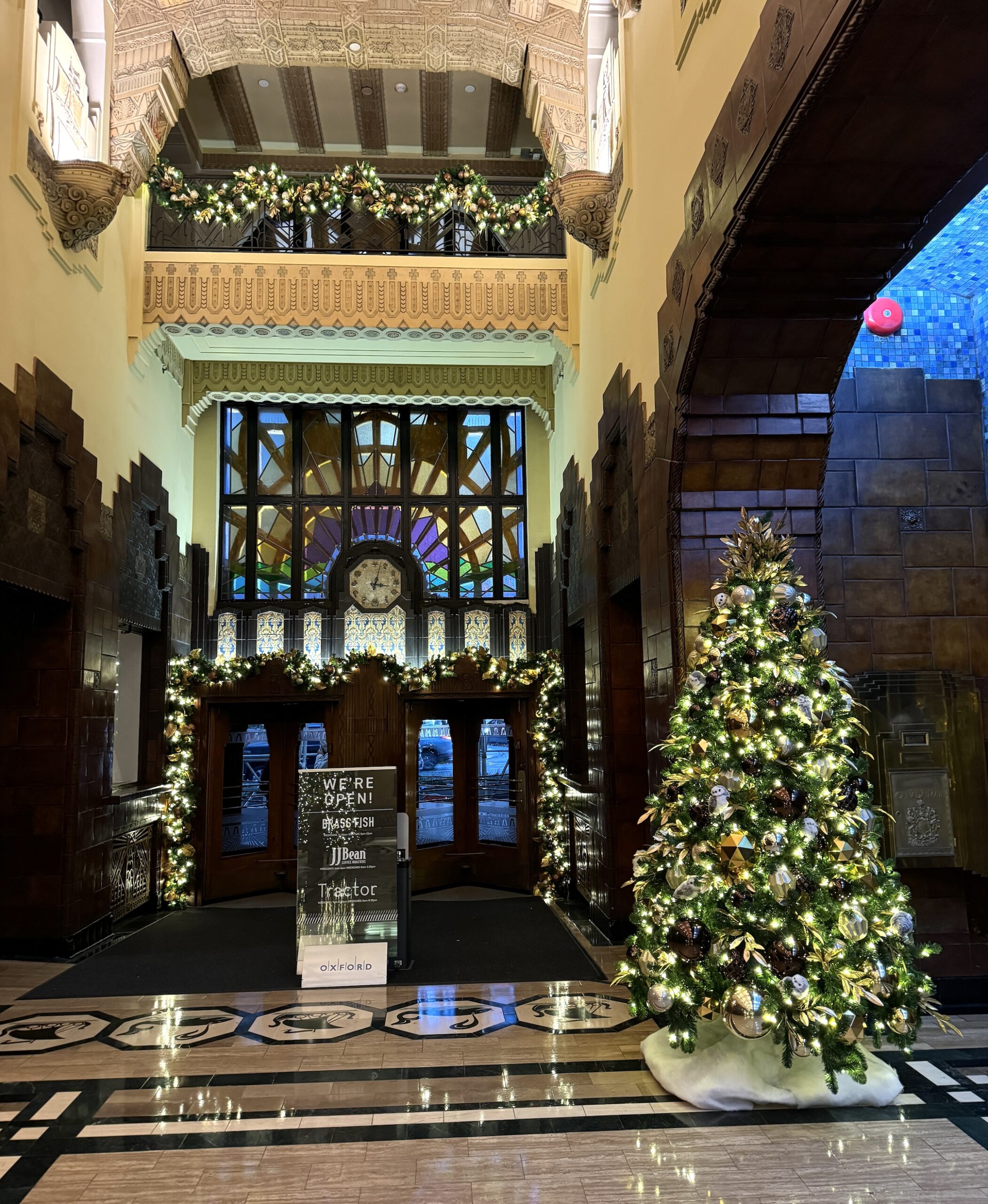 Mixed metallics Christmas tree with gold, silver, and bronze ornaments, paired with illuminated garlands, decorating the elegant lobby of the Marine Building.