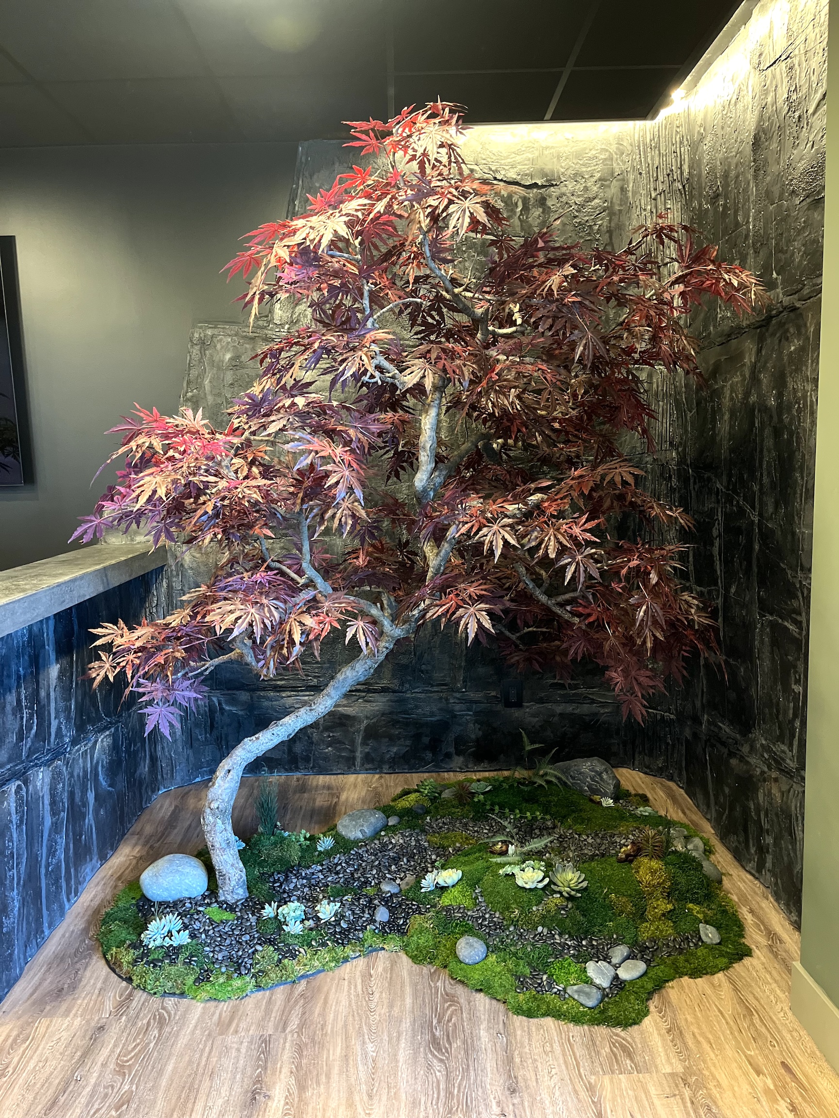 Faux Japanese maple bonsai tree with rich red foliage, set in a decorative moss and stone landscape.