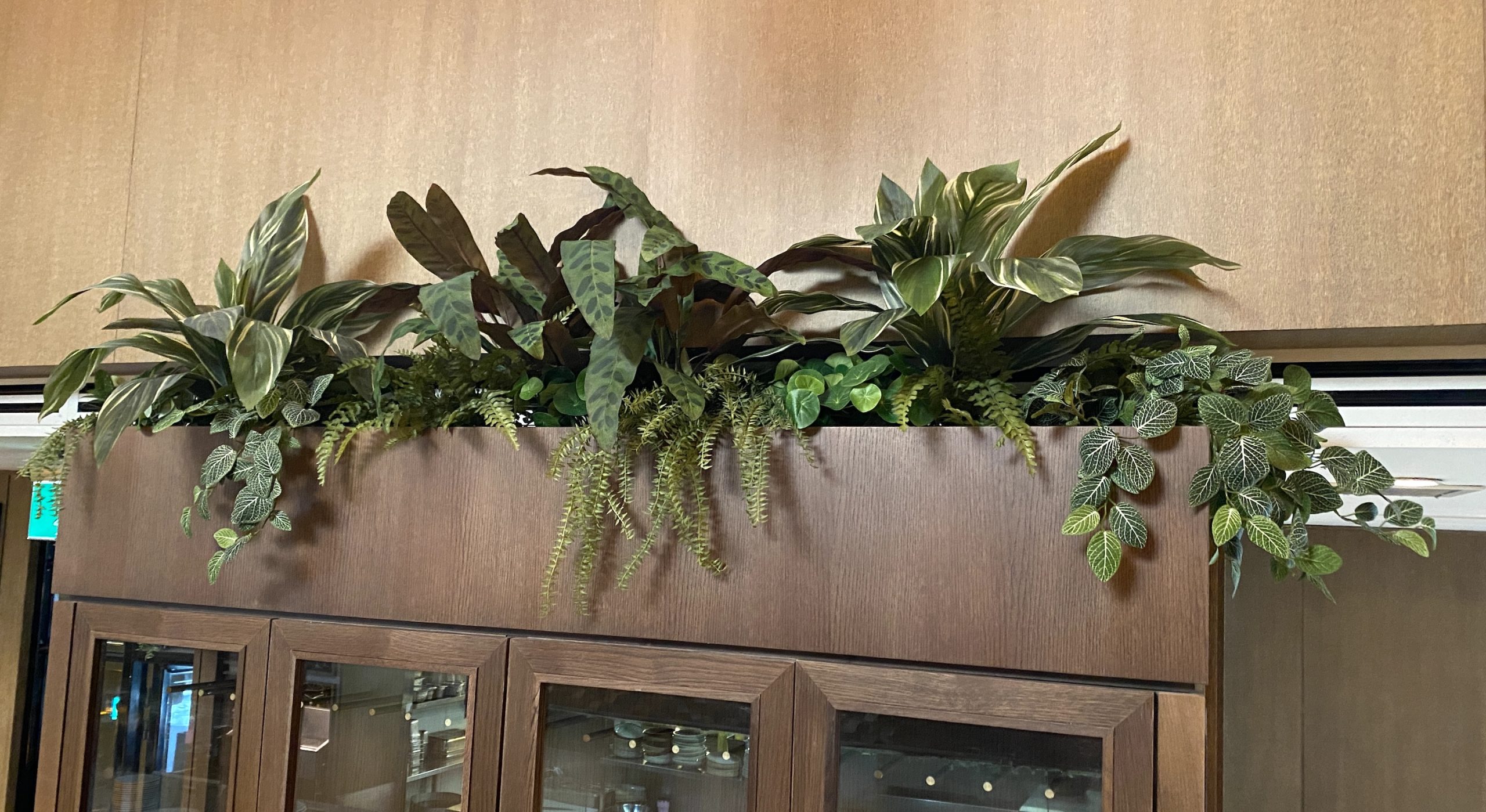 Overhead planter filled with faux plants enhancing a restaurant interior with lush greenery.