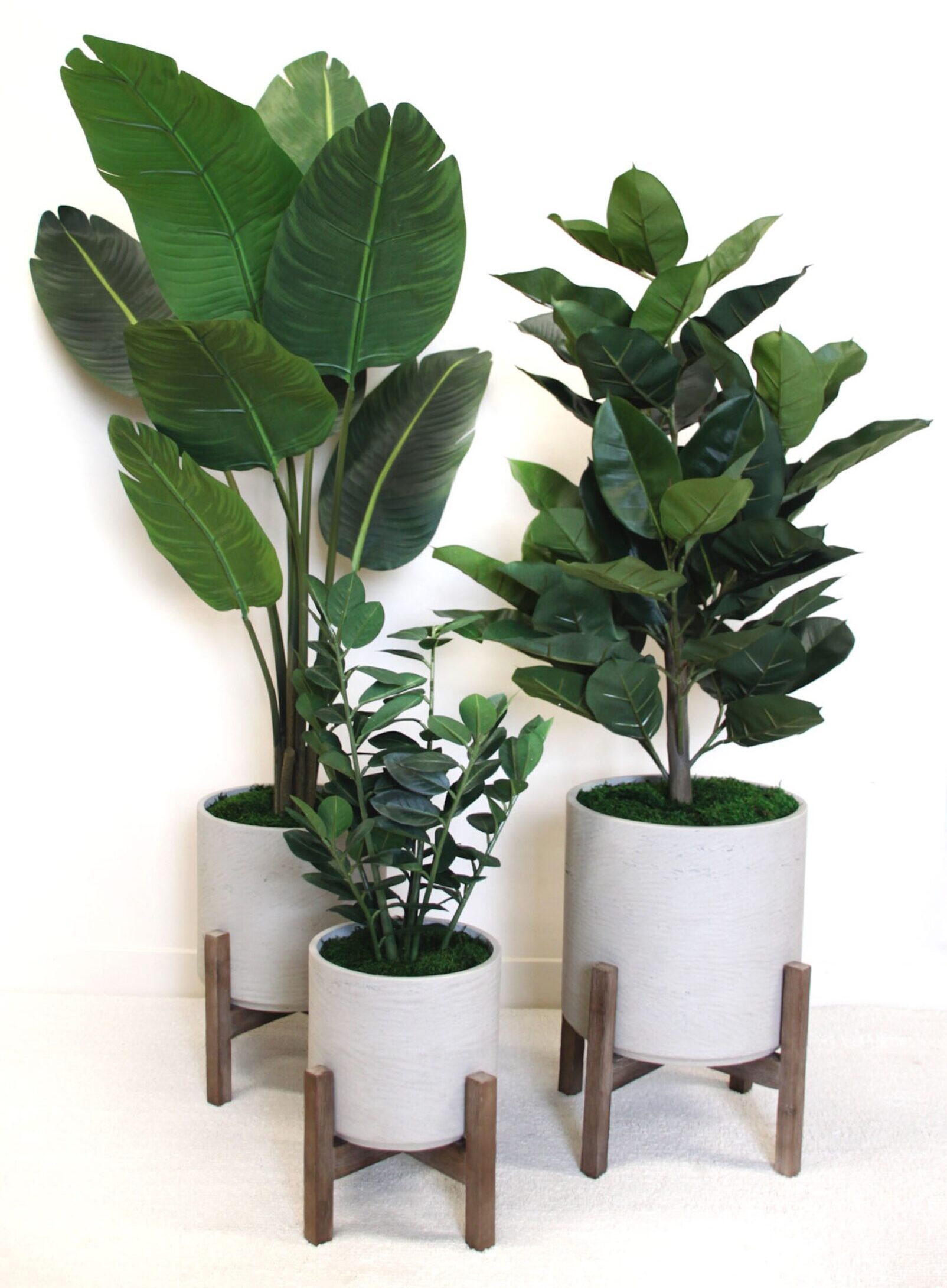 Artificial potted plants in modern concrete planters with wooden stands. Features faux banana, rubber, and ficus trees, adding greenery to contemporary interiors.