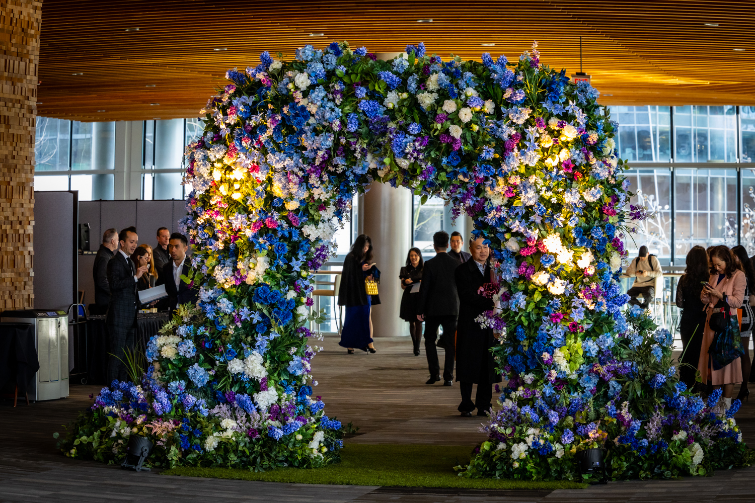 A grand artificial floral entrance arch with vibrant blue, purple, and white blooms, creating a stunning focal point at a corporate event.