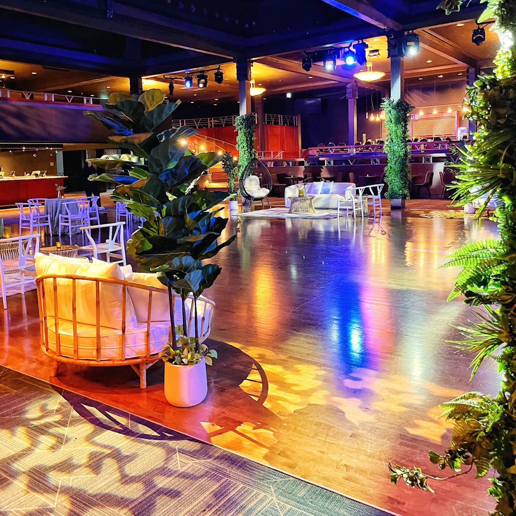 A vibrant event space at Commodore Ballroom featuring fake potted plants, lush faux greenery, and modern lounge seating.