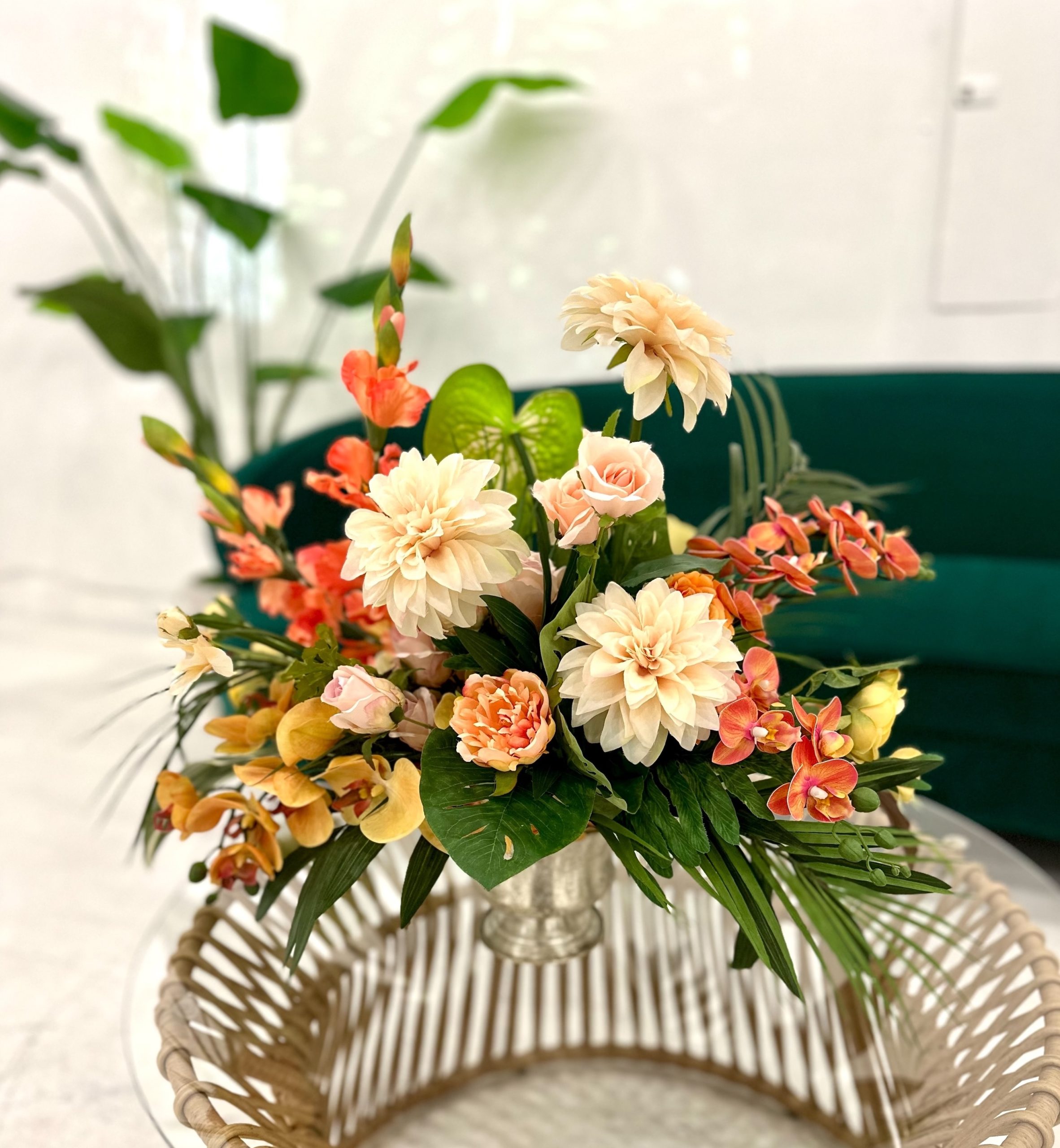 A vibrant fresh floral centerpiece with peach and coral blooms, elegantly arranged in a silver vase for event décor.