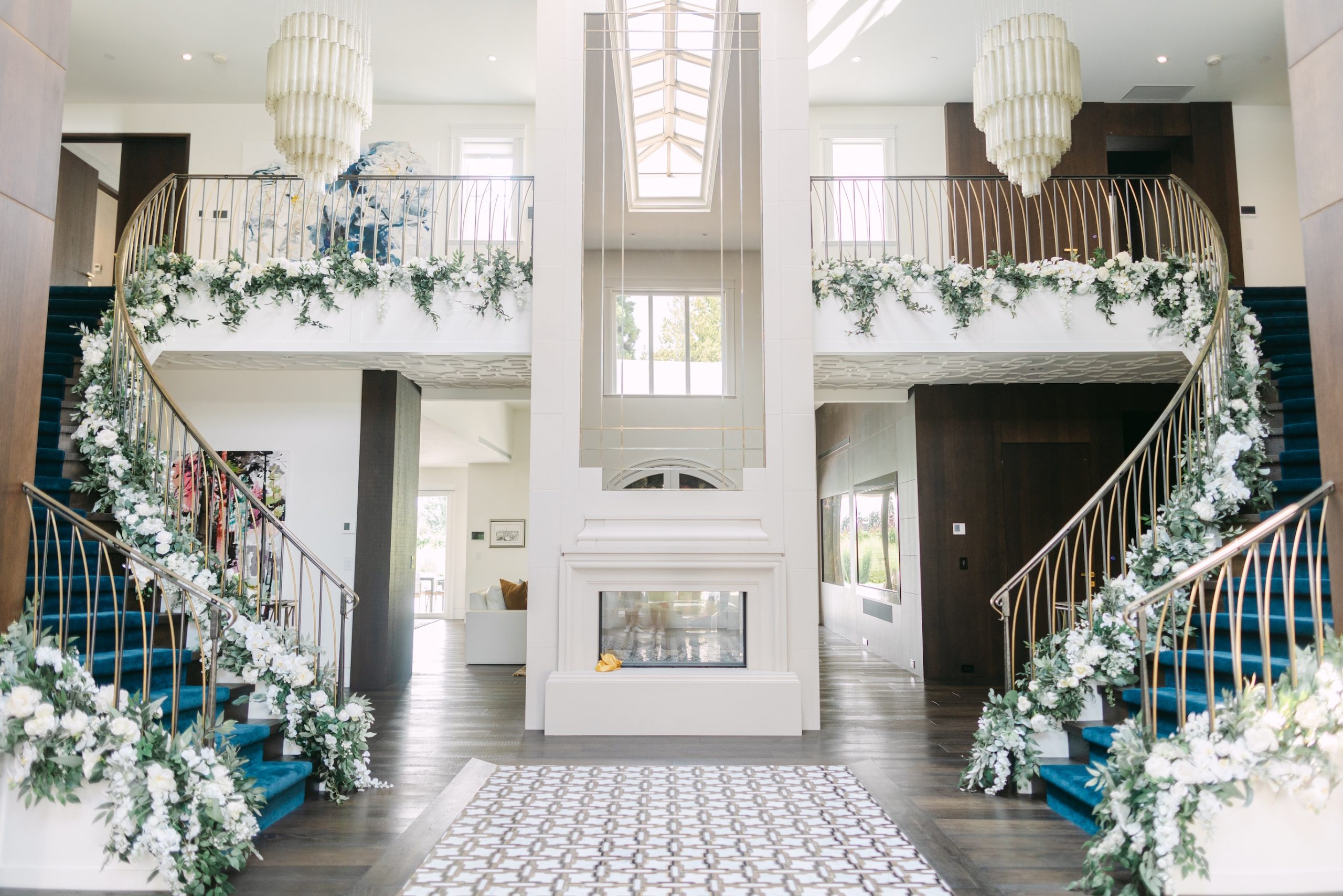 Elegant staircase adorned with artificial white floral garlands and greenery, creating a luxurious wedding decor display in a Vancouver venue.