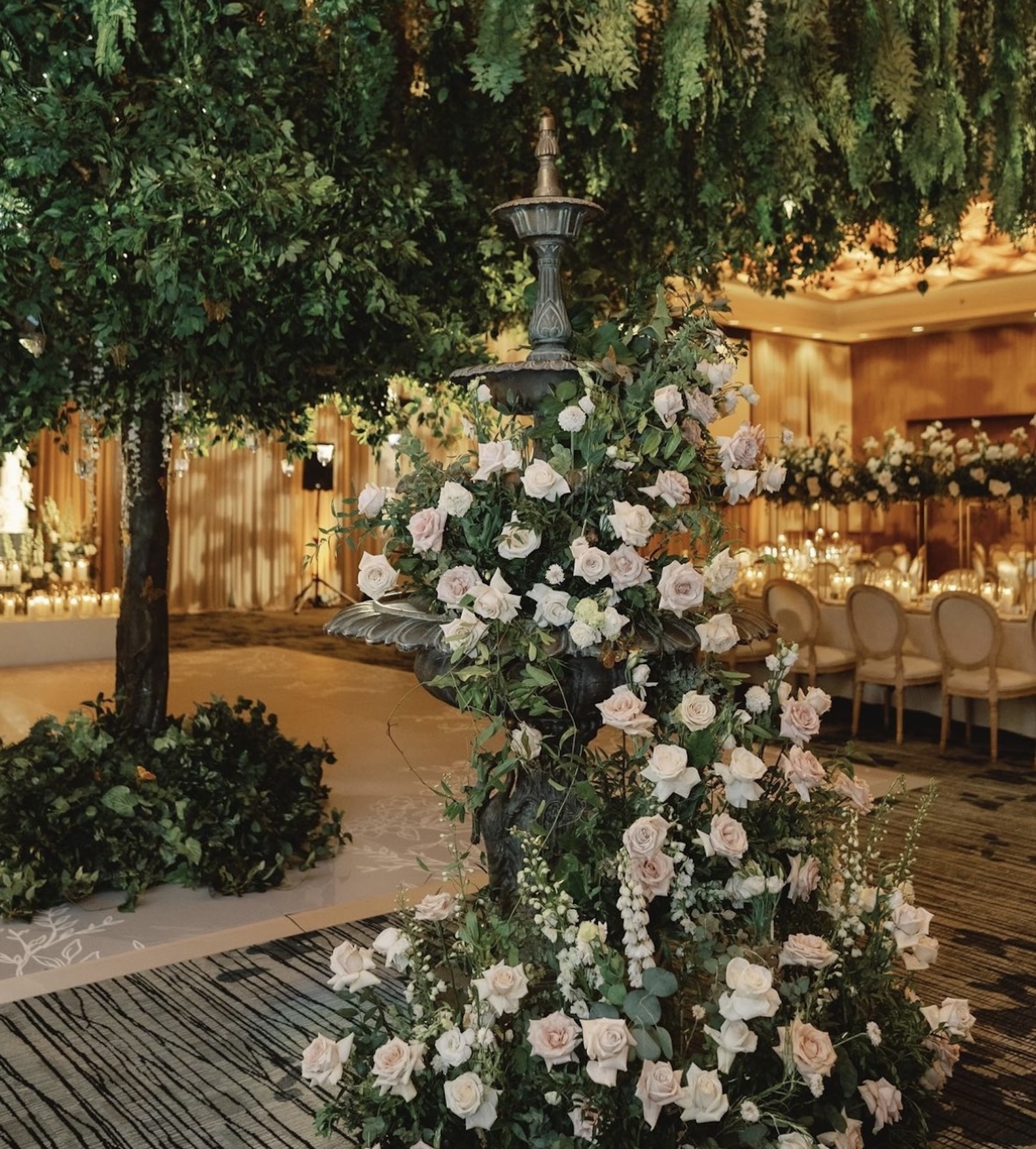 Luxurious wedding floral design featuring a grand canopy tree, cascading roses, and an elegant fountain centerpiece.