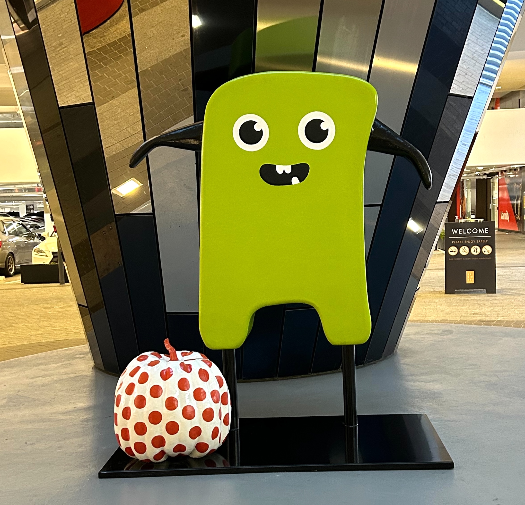 Custom Halloween decor featuring a green monster sculpture and a red polka-dot pumpkin at Brentwood.