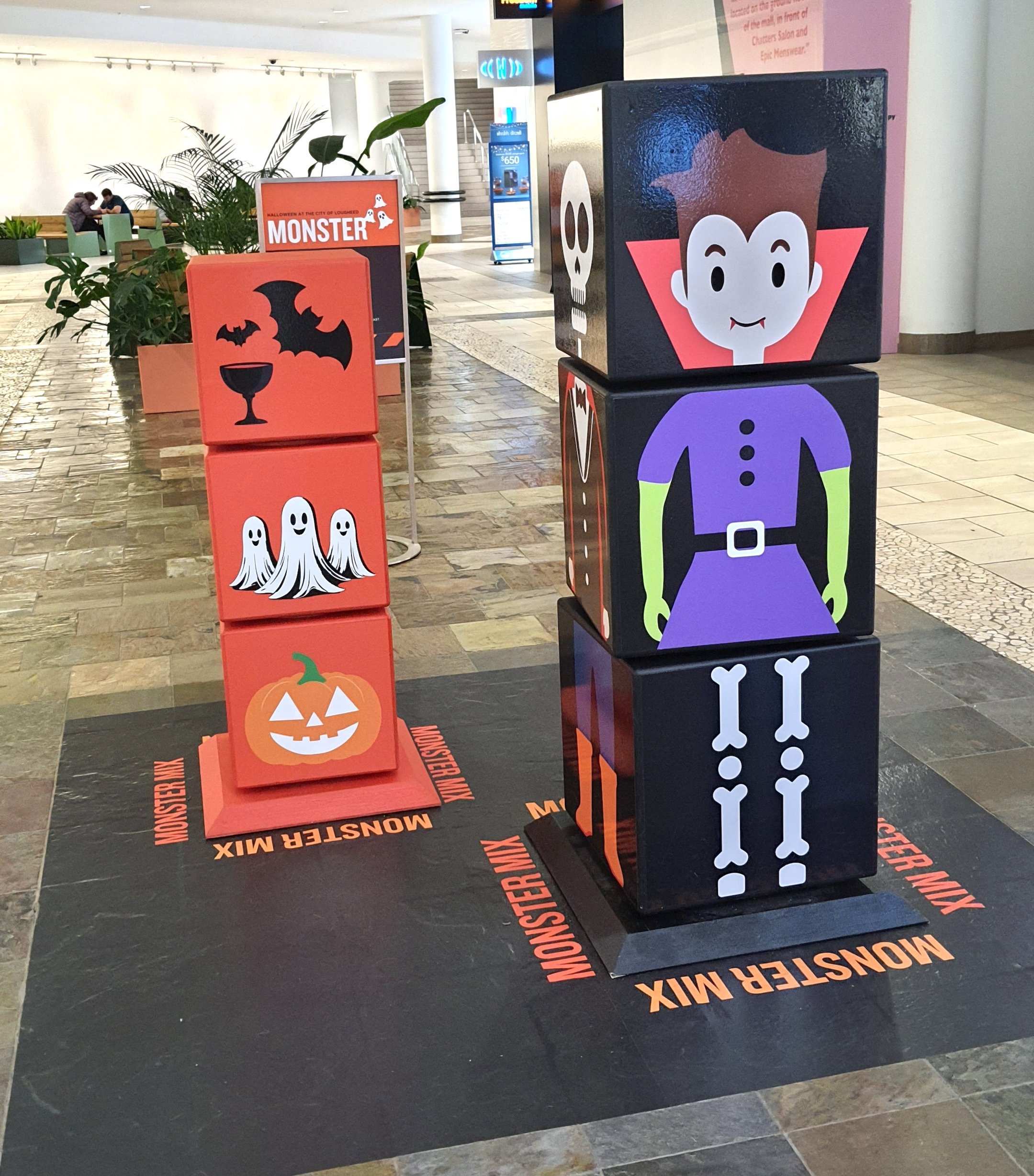 Halloween-themed stacking cubes with illustrated characters, including a vampire, skeleton, pumpkin, and ghosts, as part of an interactive display at The City of Lougheed Shopping Centre.