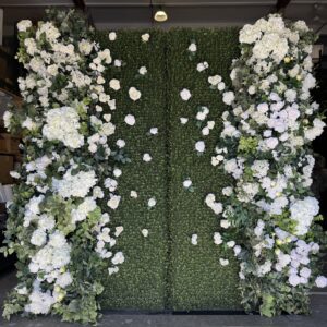 White and green floral wall backdrop with lush greenery and cascading white blooms by Greenscape Design.