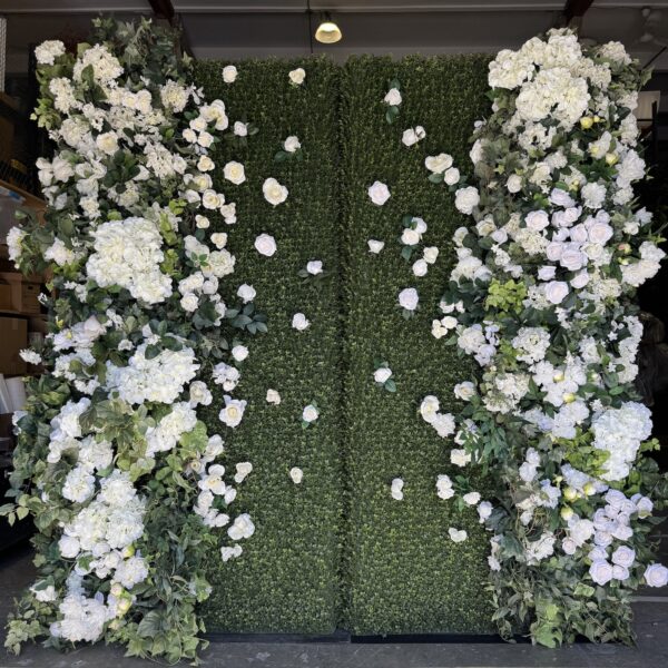 White and green floral wall backdrop with lush greenery and cascading white blooms by Greenscape Design.