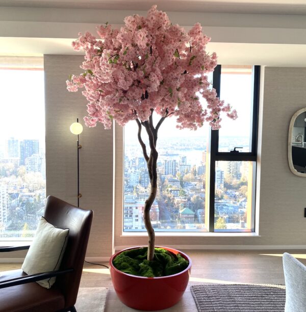 Artificial cerise cherry blossom tree in a modern red bowl planter, styled in a contemporary high-rise living space with city views.