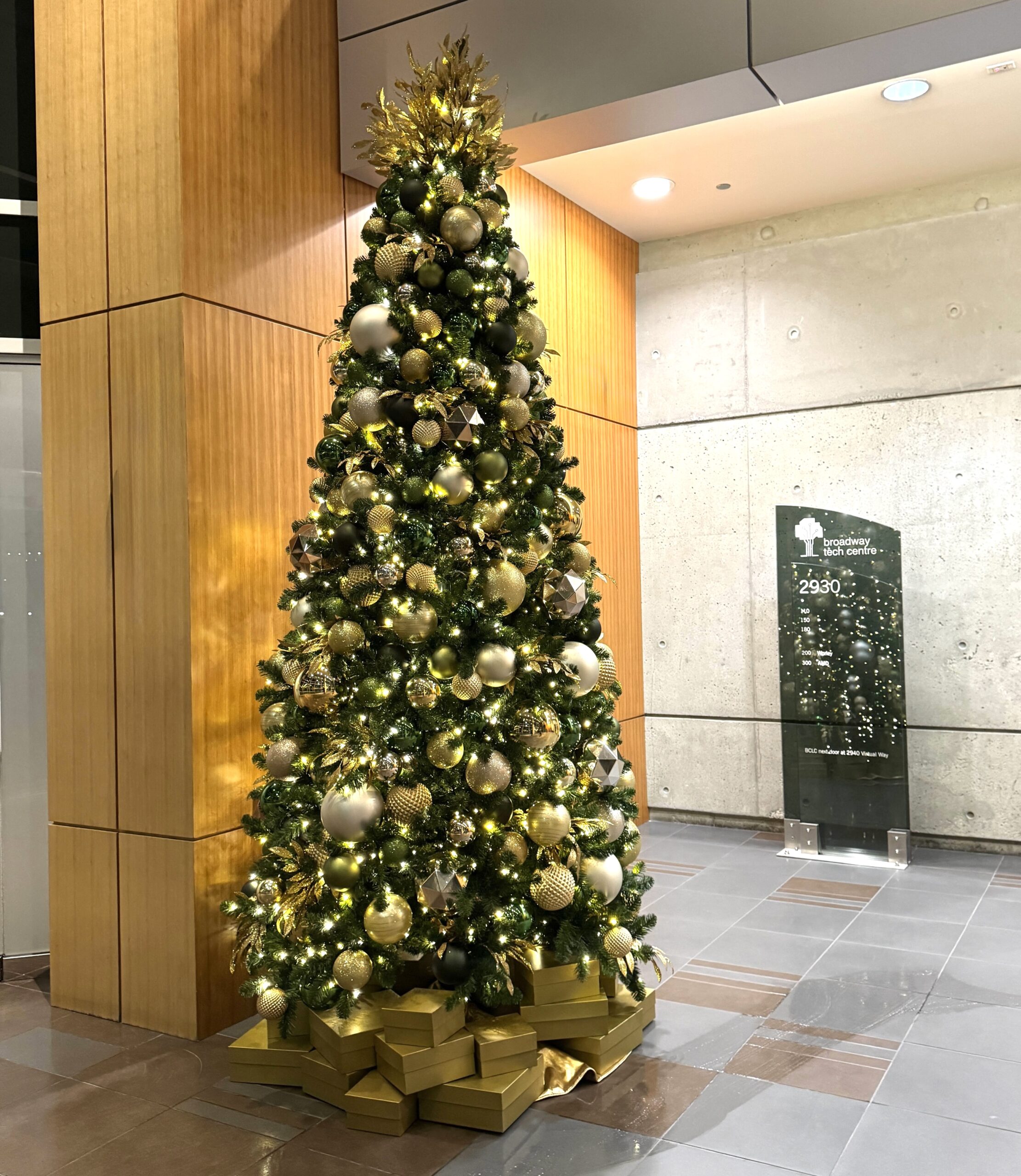 Green and gold themed faux Christmas tree in office lobby