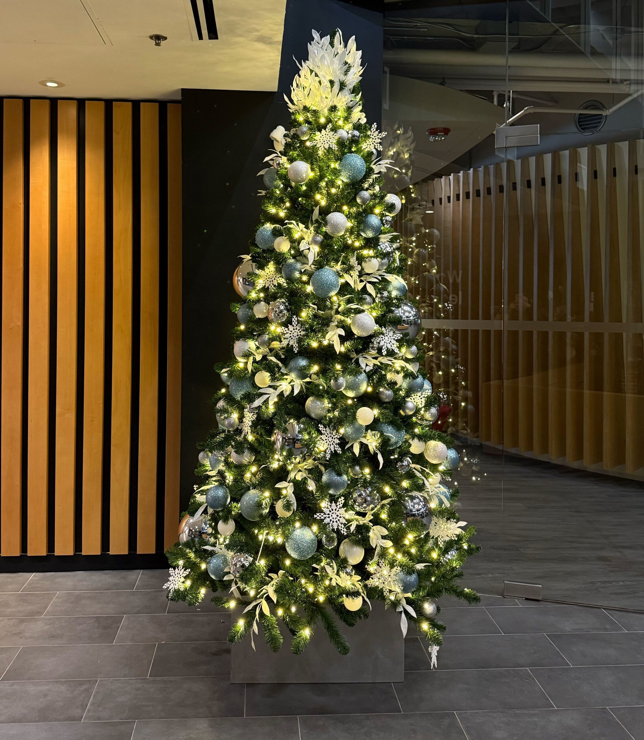 Icy blue and white themed Christmas tree in a commercial office space.
