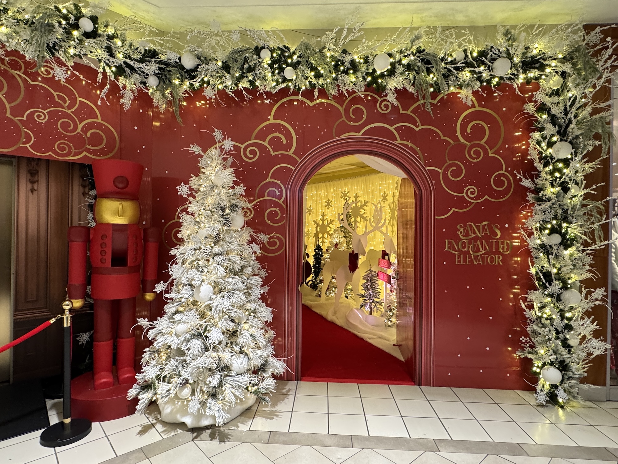 Santa’s Enchanted Elevator walk-through entrance with nutcracker and flocked tree in shopping centre