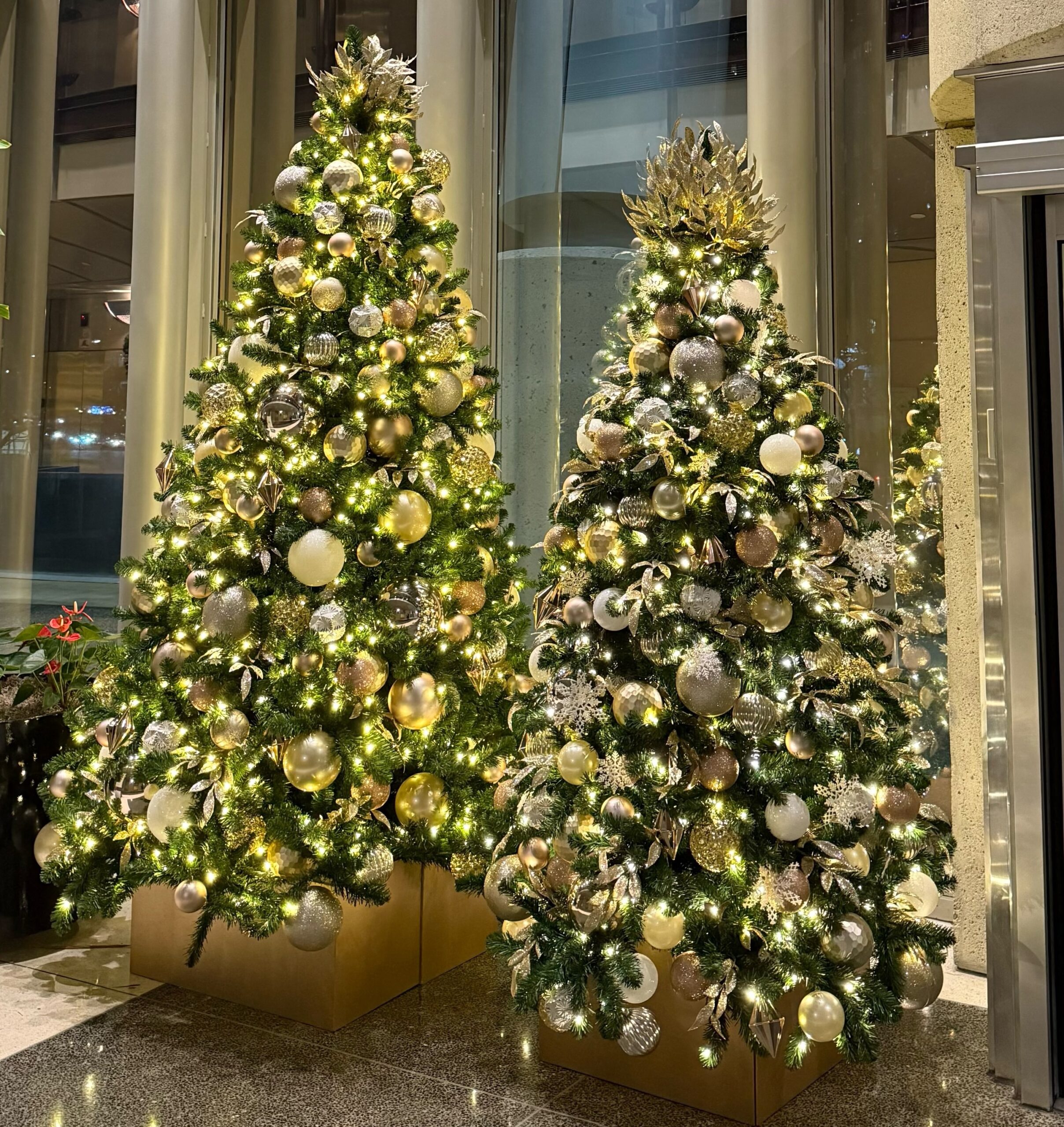 Two mixed metallic themed Christmas trees in corporate space