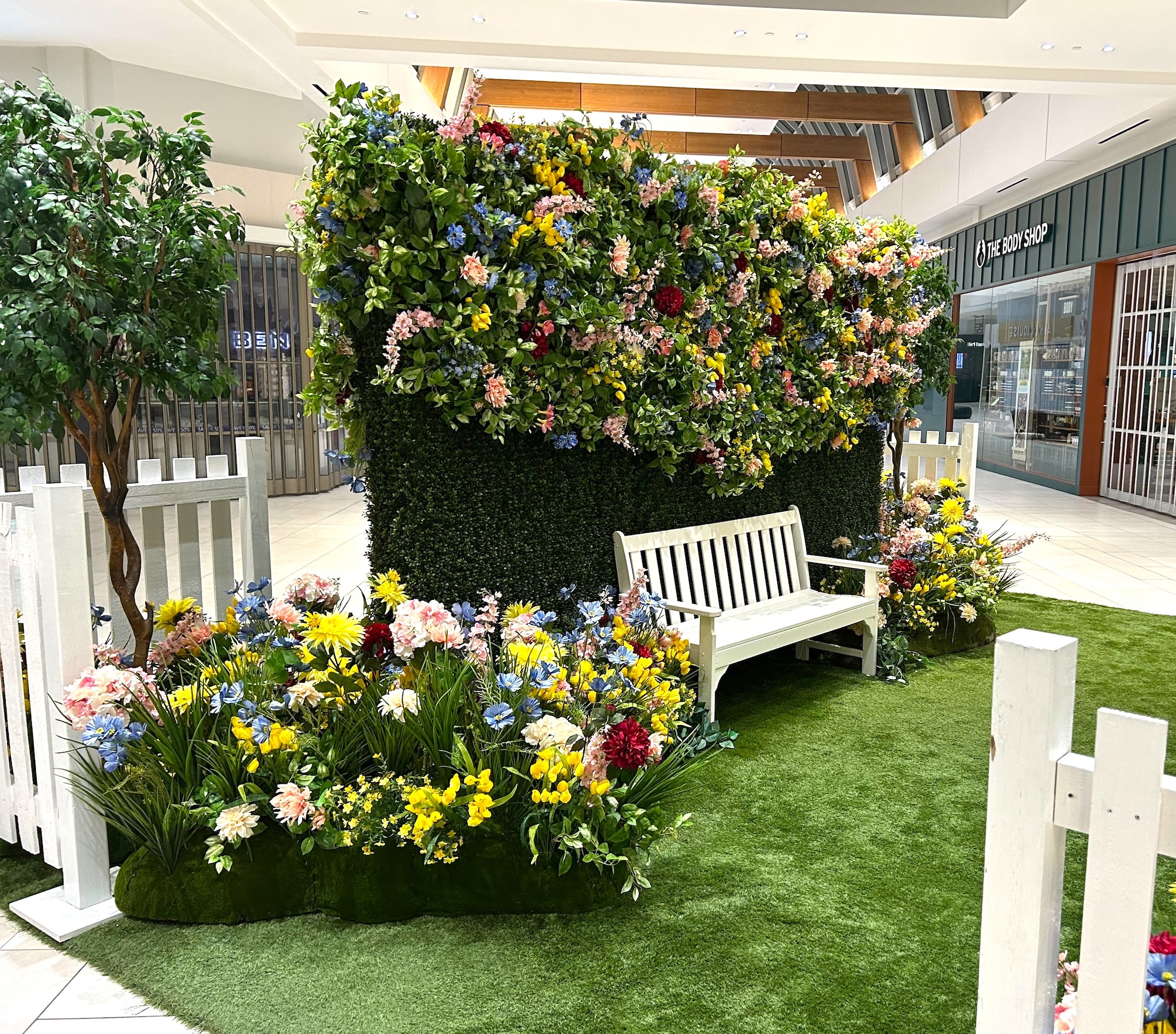 Easter photo area with white bench and large floral arrangement backdrop