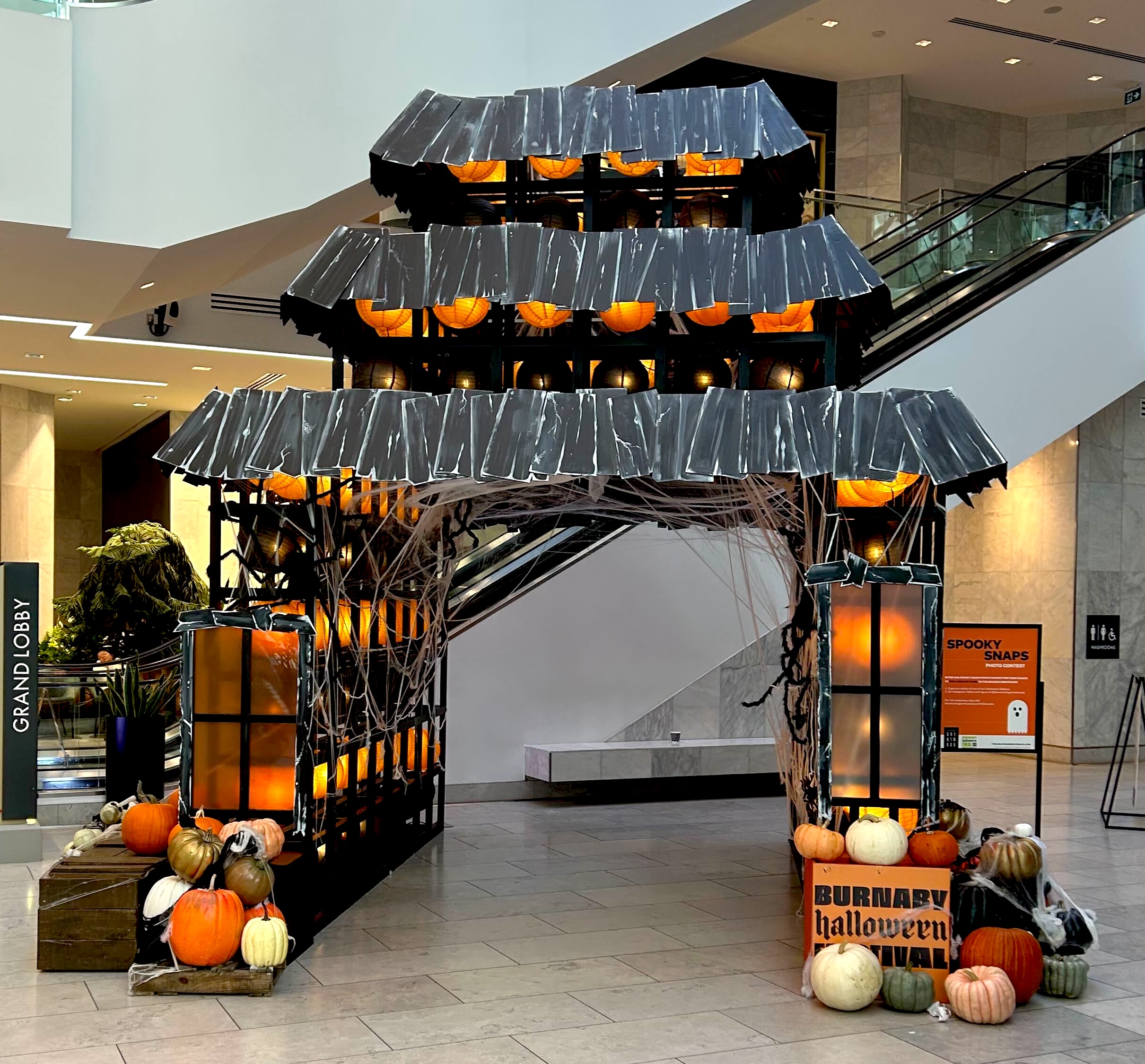 Haunted house themed Halloween arch display with pumpkins in shopping mall
