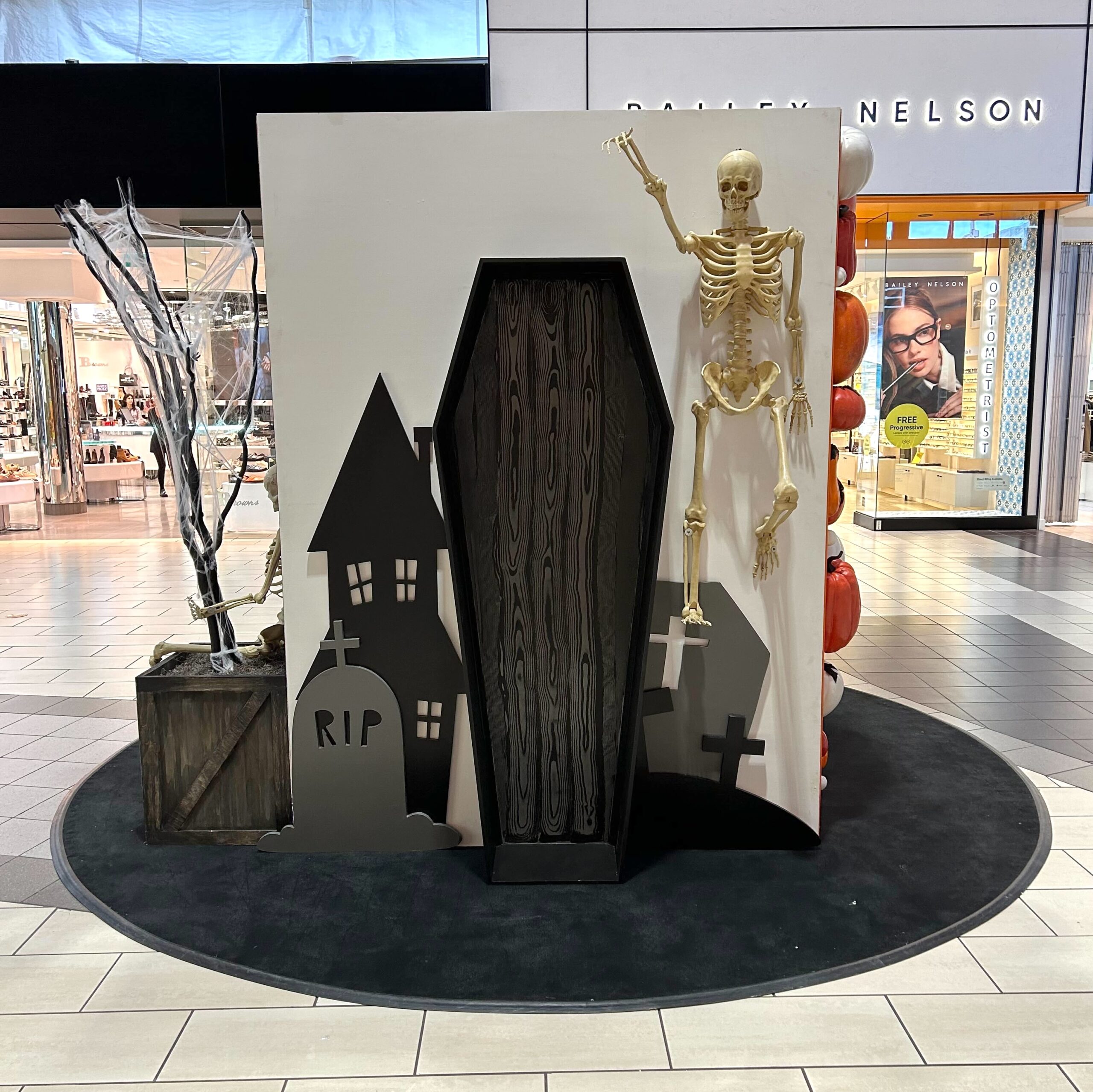 Spooky Halloween display with haunted house silhouettes and skeleton figure in mall