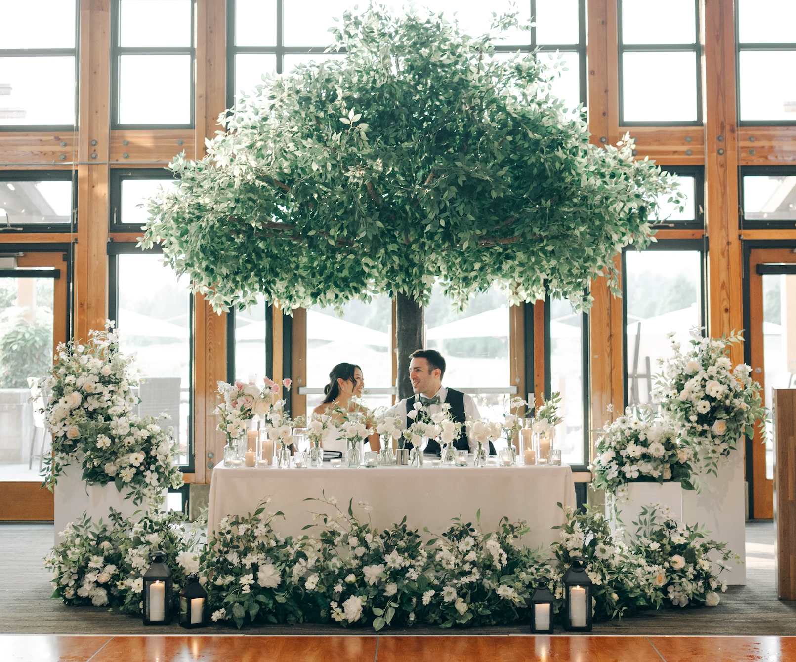Sweetheart table with greenery and faux tree backdrop.