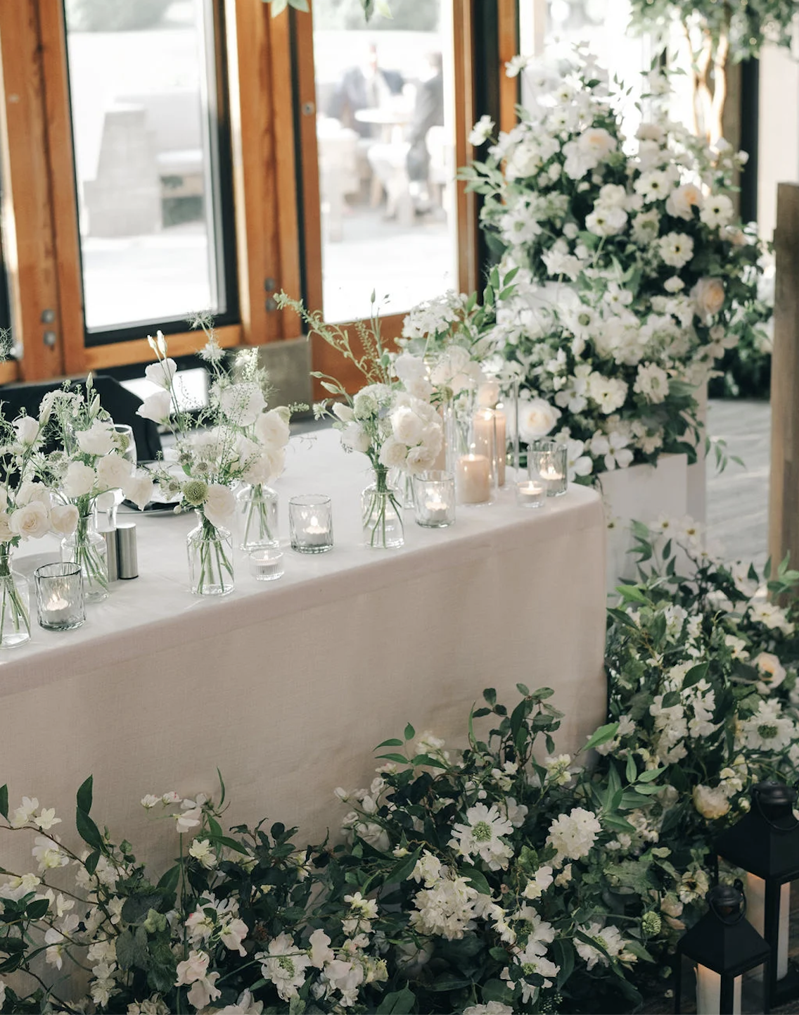 Wedding head table with white floral arrangements and greenery